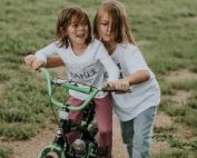 Girl helping friend ride a bike